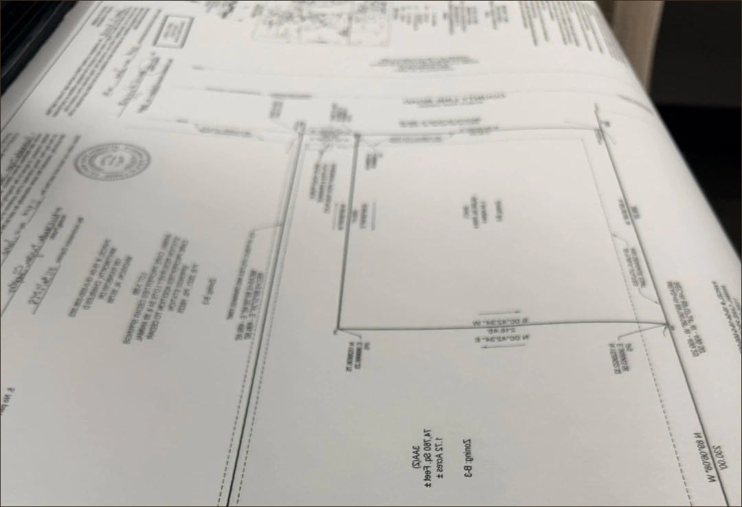 Desktop_Meet_the_Doctor_Excellence_And A close-up photo of a technical document or blueprint with various measurements, labels, and text, showing a rectangular plot and some official stamps partially visible.